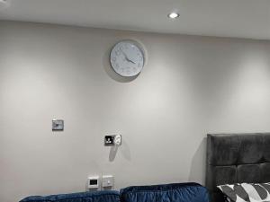 a clock on a white wall above a couch at Double En Suite Room Newcastle Upon Tyne in Derwent Haugh +24 photos