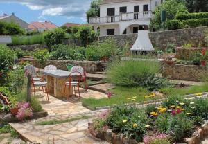 einen Garten mit einem Tisch, Stühlen und Blumen in der Unterkunft Apartment Ljerka in Malinska