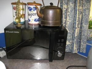 eine Mikrowelle mit einer Teekanne darüber in der Unterkunft Cosy character cottage conservation area in St Albans + 3 Fotos