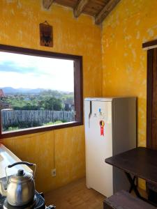 a kitchen with a white refrigerator and a window at Sunset Lagoon Praia do Rosa in Praia do Rosa