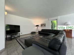 a living room with a leather couch and a tv at Villa EMG Gelsenkirchen Essen Dortmund - Gelsenkirchen in Gelsenkirchen