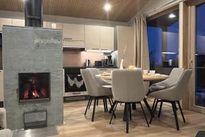 a dining room with a fireplace and a table and chairs at Villa Naali E in Kilpisjärvi