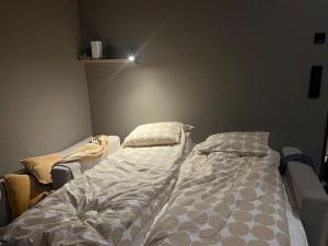 an unmade bed in a bedroom with a light on the wall at Villa Naali E in Kilpisjärvi