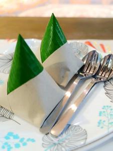 a plate with forks and spoons with green napkins at Al Funduq Motel in Jitra +18 photos