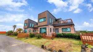 a large brick house with a wooden fence at Jeju Jongdal Private Pension in Jeju