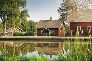 a red house next to a pond in front of a house at Hajstorp Slusscafé & Vandrarhem in Töreboda