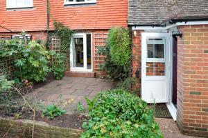 una casa de ladrillo con una puerta blanca y algunos arbustos en Hassocks Hideaway with Parking Garden, en Hassocks