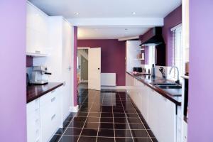 cocina con armarios blancos y suelo de baldosa marrón en Hassocks Hideaway with Parking Garden, en Hassocks