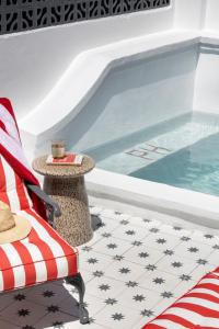 Una piscina con una silla y una mesa al lado de una piscina. en Petit Pineapple House, en Ciudad del Cabo