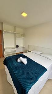 a bedroom with a large bed with two towels on it at Verdes Pássaros Apart Hotel in Florianópolis