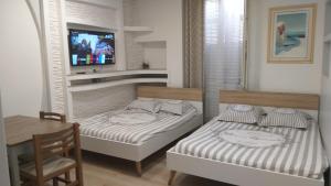 two beds in a room with a table and a tv at Excellent Studio au cœur historique de Fréjus in Fréjus