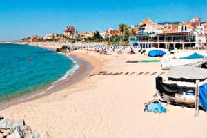 a beach with umbrellas and people in the water at Apto en la playa a 20 min en tren de Barcelona in Cabrera de Mar