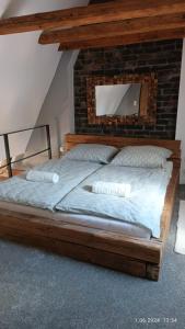 a bedroom with a wooden bed with a brick wall at Kapka wina in Toruń