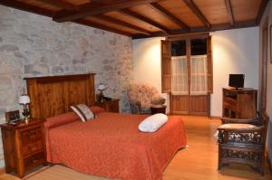 a bedroom with a bed and a stone wall at Hotel Casona De Tresali in Argüero