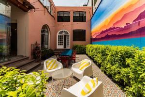een terras met witte stoelen en een muurschildering aan de zijkant van een gebouw bij Roma Elite Residence Spacious and Elegant in Mexico-Stad