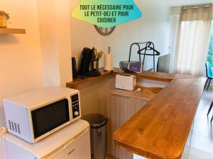 a microwave sitting on top of a table in a kitchen at Le Pic'Vert - Ideal couples & professionals - FREE Parking - 400m Hospital - 15min Train station & HISTORIC Center - Air conditionner - Calm & Cosy in Bergerac