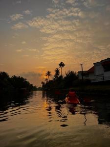 a person in a kayak on a river at sunset at Birdwatching and kaya king for backpackers in Alleppey