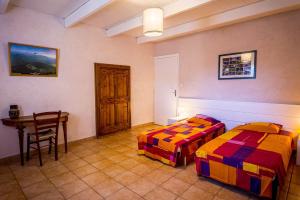 two beds in a room with a table and a desk at Gîte Spacieux et Authentique au Coeur de la Nature in Le Poët
