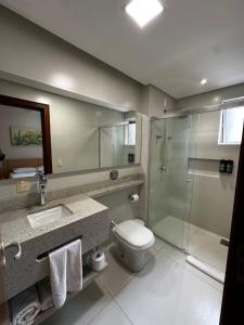 a bathroom with a toilet and a glass shower at Diaudi Hotel in São José