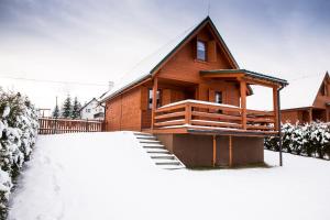 una cabaña de madera en la nieve con un patio cubierto de nieve en Domki Krótki Szpic en Istebna