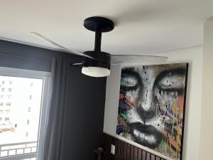 un ventilador de techo en una sala de estar con una pintura en Studio próximo ao teatro Renault e hospitais, en São Paulo