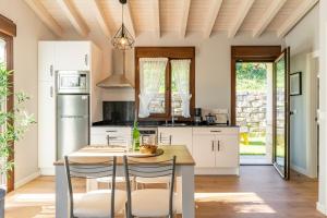 a kitchen with white cabinets and a table and chairs at Apartamentos Cuetumerin in Cangas de Onís