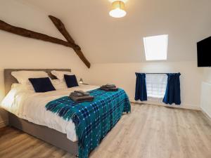 a bedroom with a bed with blue sheets and a window at Y Côr in Corwen