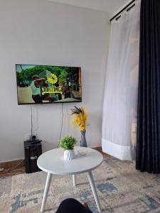 a living room with a white table and a tv at Lymak Studio airbnb in Ongata Rongai 