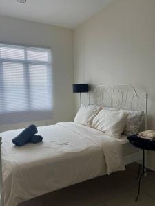 Un dormitorio con una cama blanca y una ventana. en Kajang MRT suites, en Kajang