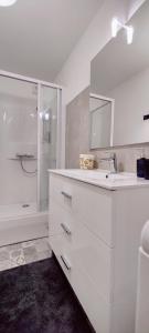 a white bathroom with a sink and a shower at Le Corsaire in Granville