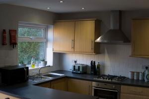 a kitchen with wooden cabinets and a sink and a stove at Entire 3-bed house near Cheltenham racecourse and town in Gloucestershire
