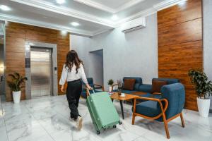 a woman walking through a lobby with a suitcase at Parklane Hotel in Tashkent
