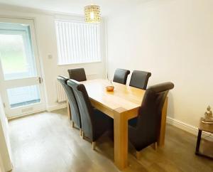 a dining room with a wooden table and black chairs at 3 Double Bedrooms, Lancashire Townhouse, Free Parking in Upholland