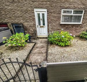 a house with a white door and two bushes at 3 Double Bedrooms, Lancashire Townhouse, Free Parking in Upholland