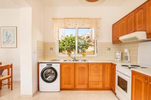 a kitchen with a washing machine and a window at Dream Villas in Lefkos Karpathou