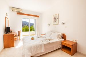 a white bedroom with a bed and a table at Dream Villas in Lefkos Karpathou