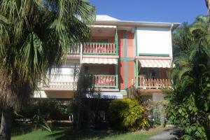 an apartment building with balconies and palm trees at Studio Ti Colibri in Sainte-Anne