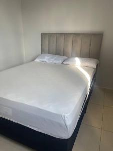 a bed with white sheets and pillows in a room at Apartamento Madero in Umuarama