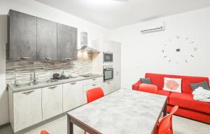 ein Wohnzimmer mit einem roten Sofa und einer Küche in der Unterkunft Gorgeous Home In Marina Di Ragusa in Marina di Ragusa