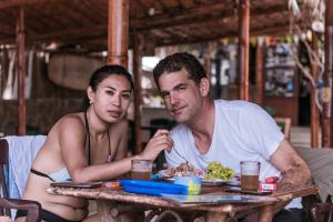 a man and woman sitting at a table with a plate of food at Hotel Relajate in Lobitos