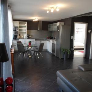 Una cocina con mesa y sillas y un refrigerador. en La Maison d'Anne, en Ribeauvillé