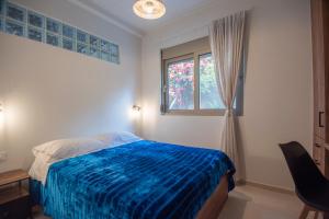 a bedroom with a blue bed and a window at Theofani's Apartment in Agios Nikolaos