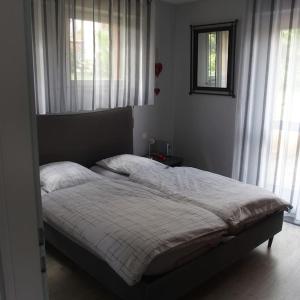 Un dormitorio con una cama en una habitación con ventanas. en La Maison d'Anne, en Ribeauvillé