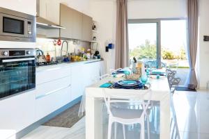 a white kitchen with a white table and chairs at Villa Regina di Marzamemi in San Lorenzo