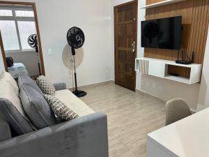 a living room with a couch and a flat screen tv at Novíssimo apt 1 quarto Centro frente à Prefeitura in Nova Friburgo
