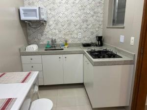 a white kitchen with a stove and a sink at Novíssimo apt 1 quarto Centro frente à Prefeitura in Nova Friburgo