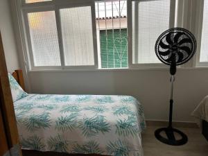 a bedroom with a bed and a fan next to a window at Novíssimo apt 1 quarto Centro frente à Prefeitura in Nova Friburgo