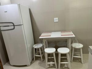 a kitchen with a counter with stools and a refrigerator at Novíssimo apt 1 quarto Centro frente à Prefeitura in Nova Friburgo