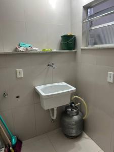 a bathroom with a white sink and a pot at Novíssimo apt 1 quarto Centro frente à Prefeitura in Nova Friburgo