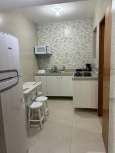 a kitchen with white cabinets and a white refrigerator at Novíssimo apt 1 quarto Centro frente à Prefeitura in Nova Friburgo